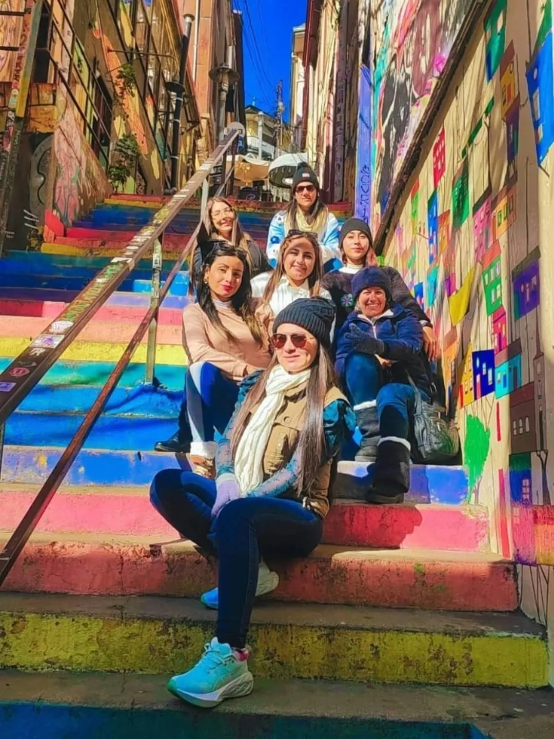 Grupo de pasajeras sentadas en una escalera pintada de colores en Valparaíso